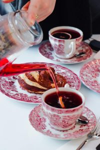 Sophisticated tea setup with ornate cups and fresh pastries being served.